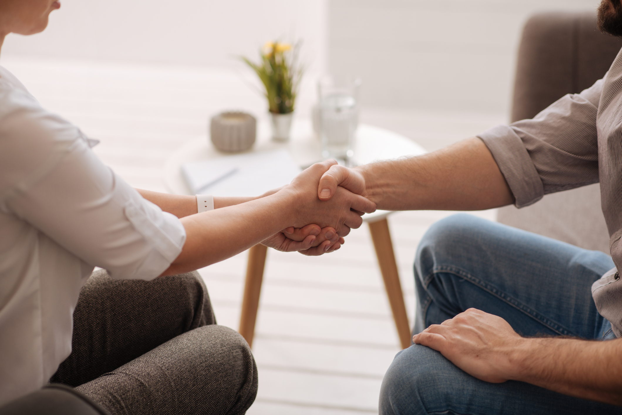 An adult in a psychotherapy session receiving a supportive handshake.