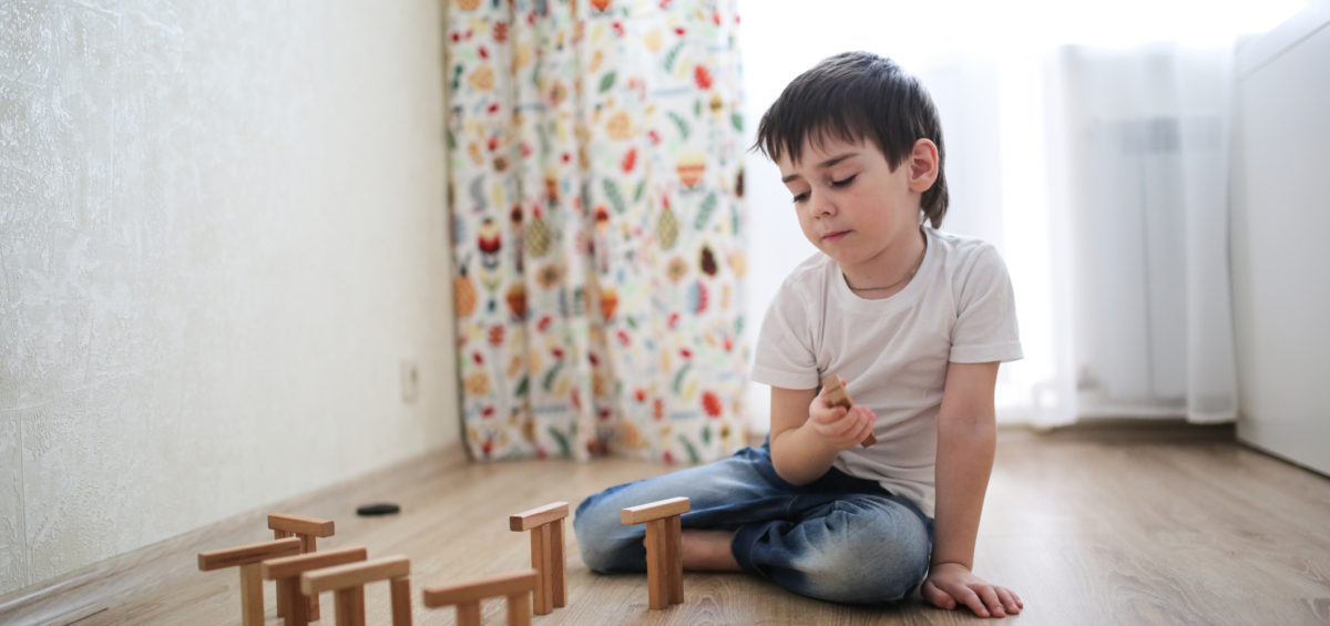 "Childhood OCD". A young child plays with blocks, balancing some on top of others in a sunny room.