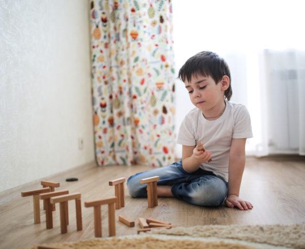 "Childhood OCD". A young child plays with blocks, balancing some on top of others in a sunny room.