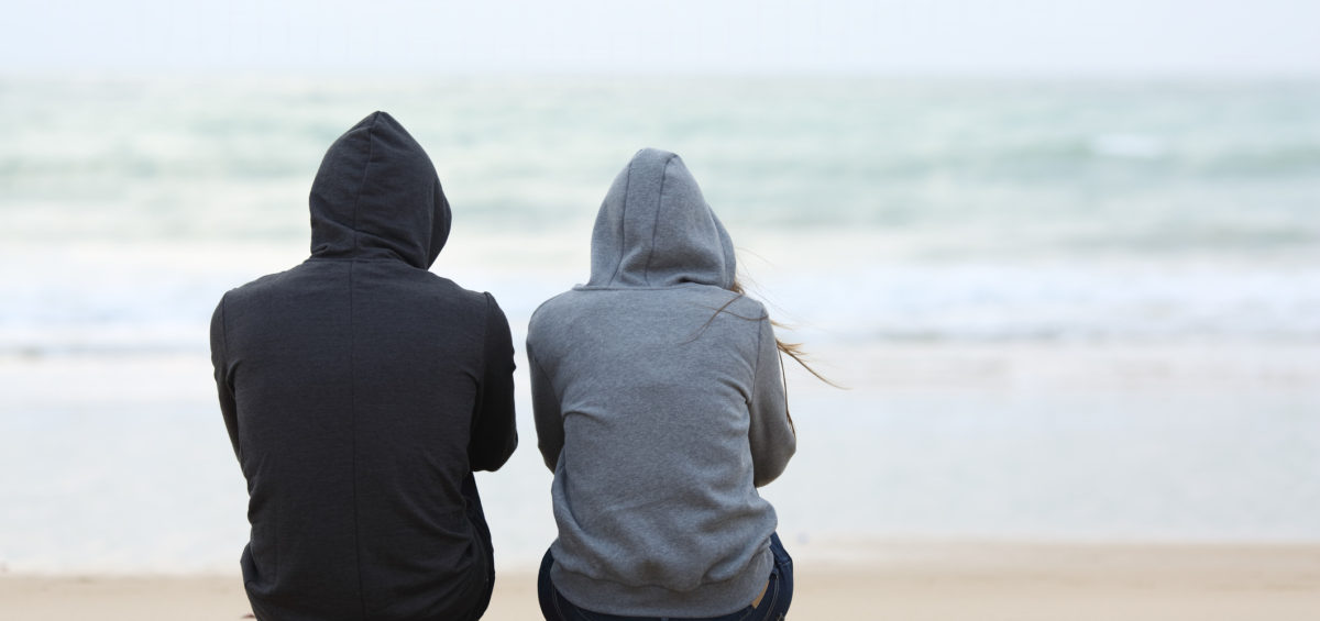 "Complicated grief: when grief lingers". Two teenagers huddle on a beach with their hoods up on a grey day.