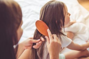 "Hair pulling (Trichotillomania)". A mother brushes her child's long hair.