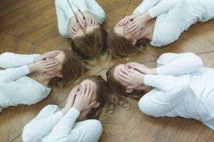 "Personality Disorders". Multiple reflections in a circle of a young woman on the floor covering her gace with her hands.