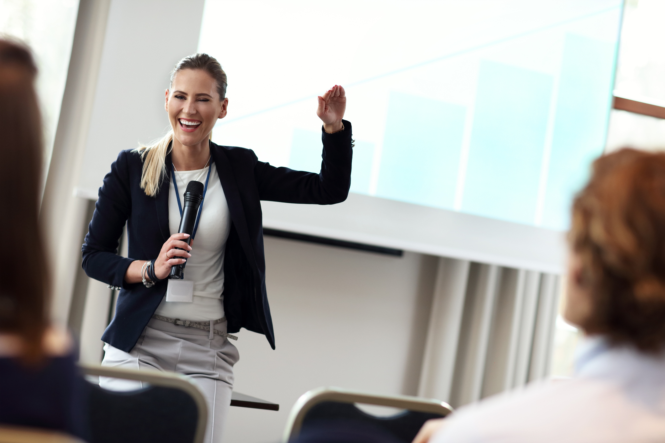 "Treating performance anxiety". A woman holding a microphone in front of a crowd shares a laugh.