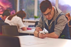 "Attention deficit hyperactivity disorder (ADHD)" A college student has a look at his phone in a common study room.