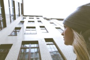 "Bipolar & Cyclothymic Disorder". A woman looks up anxiously at a wall of windows on a building.