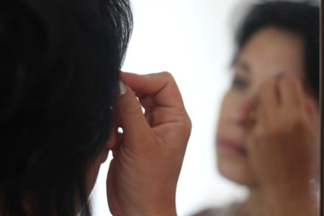 Treatment for Trichotillomania - a person looks in the mirror while touching their eyebrow.