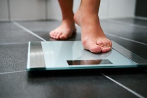 "Weight management". Feet stepping onto a scale.