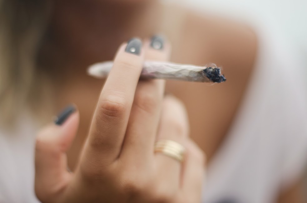 Close-up of fingerpainted nails holding a joint.