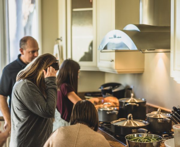 Holiday stress - A family working together in the kitchen, a woman looking stressed.