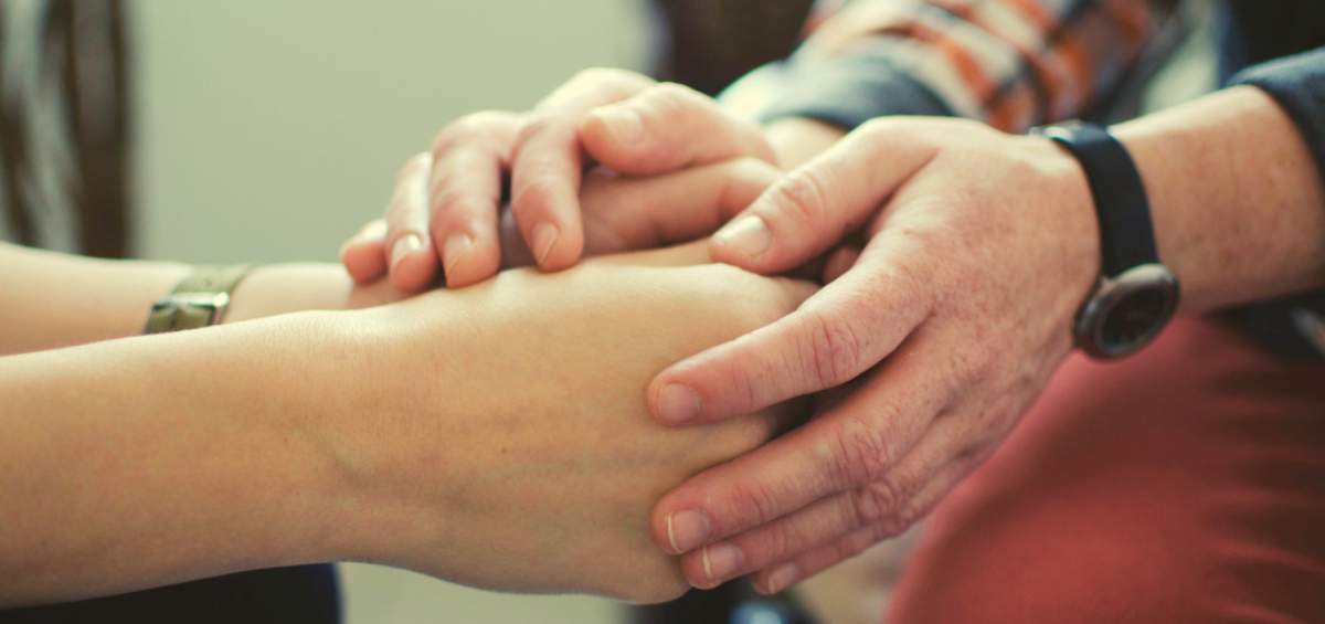 A therapist's hands comfort a client's hands.