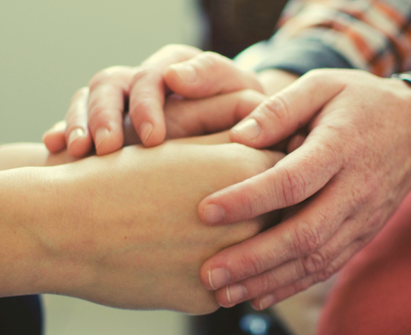 A therapist's hands comfort a client's hands.