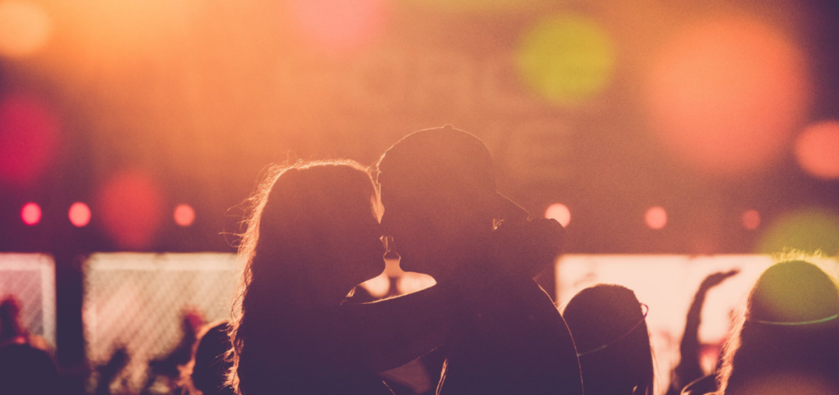 In the glow of a concert, an embracing couple is visible in silhouette.