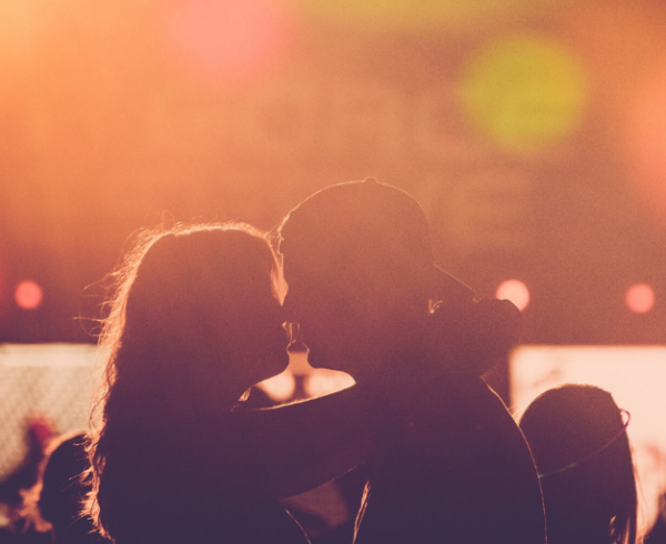 In the glow of a concert, an embracing couple is visible in silhouette.